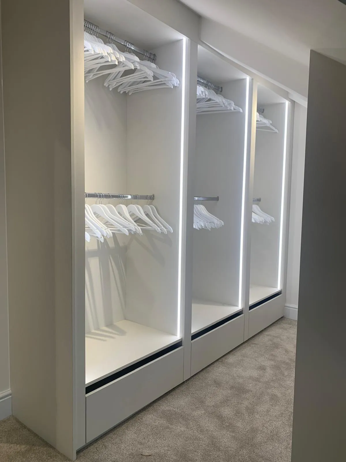 Sliding door wardrobe run and panelled feature wall in a fitted bedroom